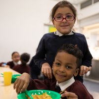 A photo of primary school boy and girl enjoying cereal for breakfast at school
